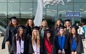 Food and nutrition students and faculty in graduation regalia standing outside in front of arena
