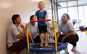 Child on a small trampoline with OT students