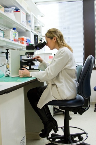 A person in a healthcare setting looks through a microscope