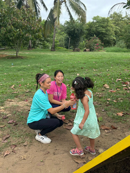 Students blowing bubbles with a child