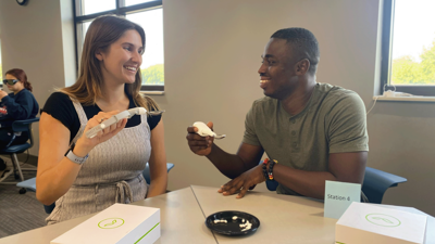 Staff member and students using adaptive utensils