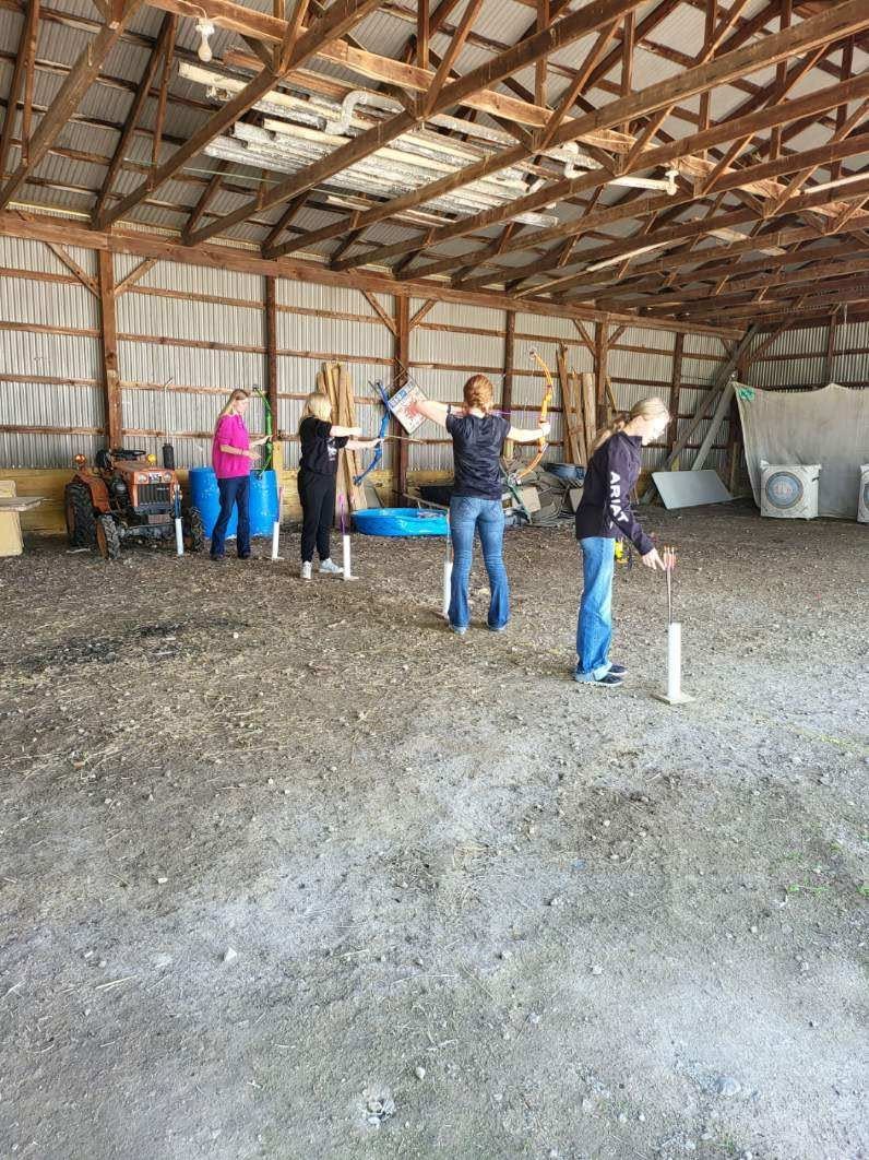 Students practice archery skills during an indoor physical education activity.