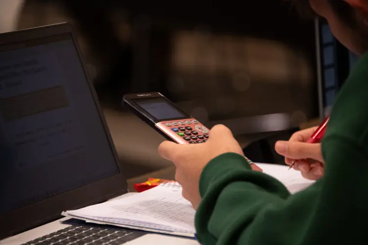 A student does schoolwork on a calculator