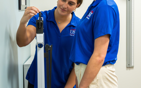 Students using scale to measure body weight in assessment room
