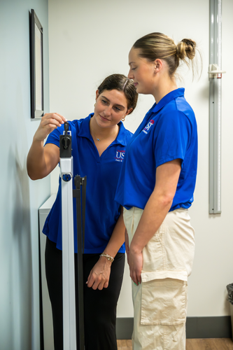 two students at the weight scale in assessment room