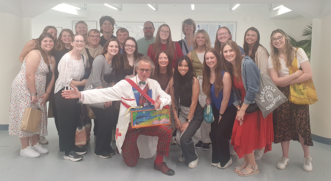 Students pose with photo of a doctor dressed as a clown