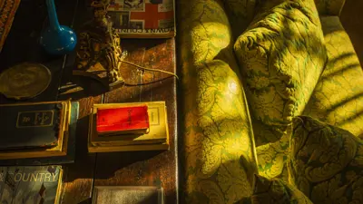 dramatically lit photo of a living room, featuring a couch and an aged table with worn books on it