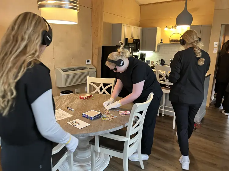 Participants doing Dementia Live simulation with headphones, gloves, and eyewear