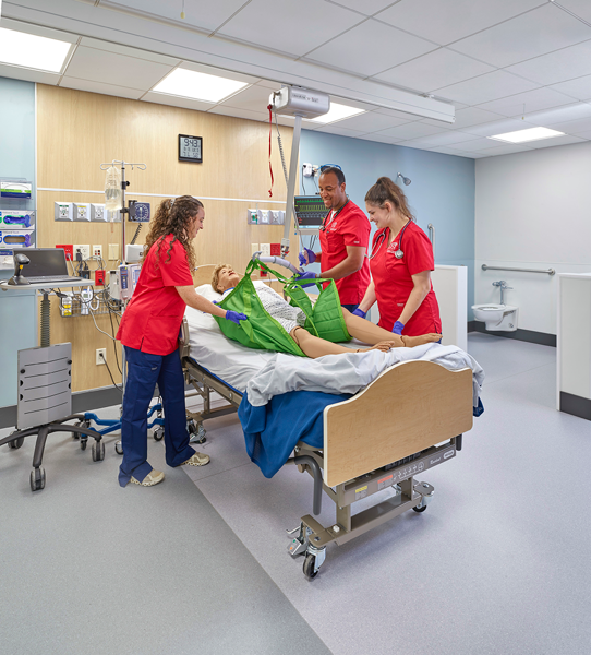 nursing students using a lift in simulation center