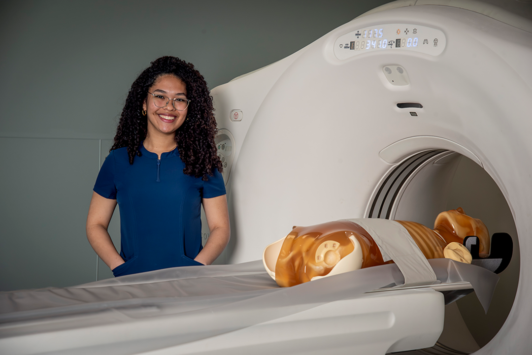 Photo of student in front of a CT simulator
