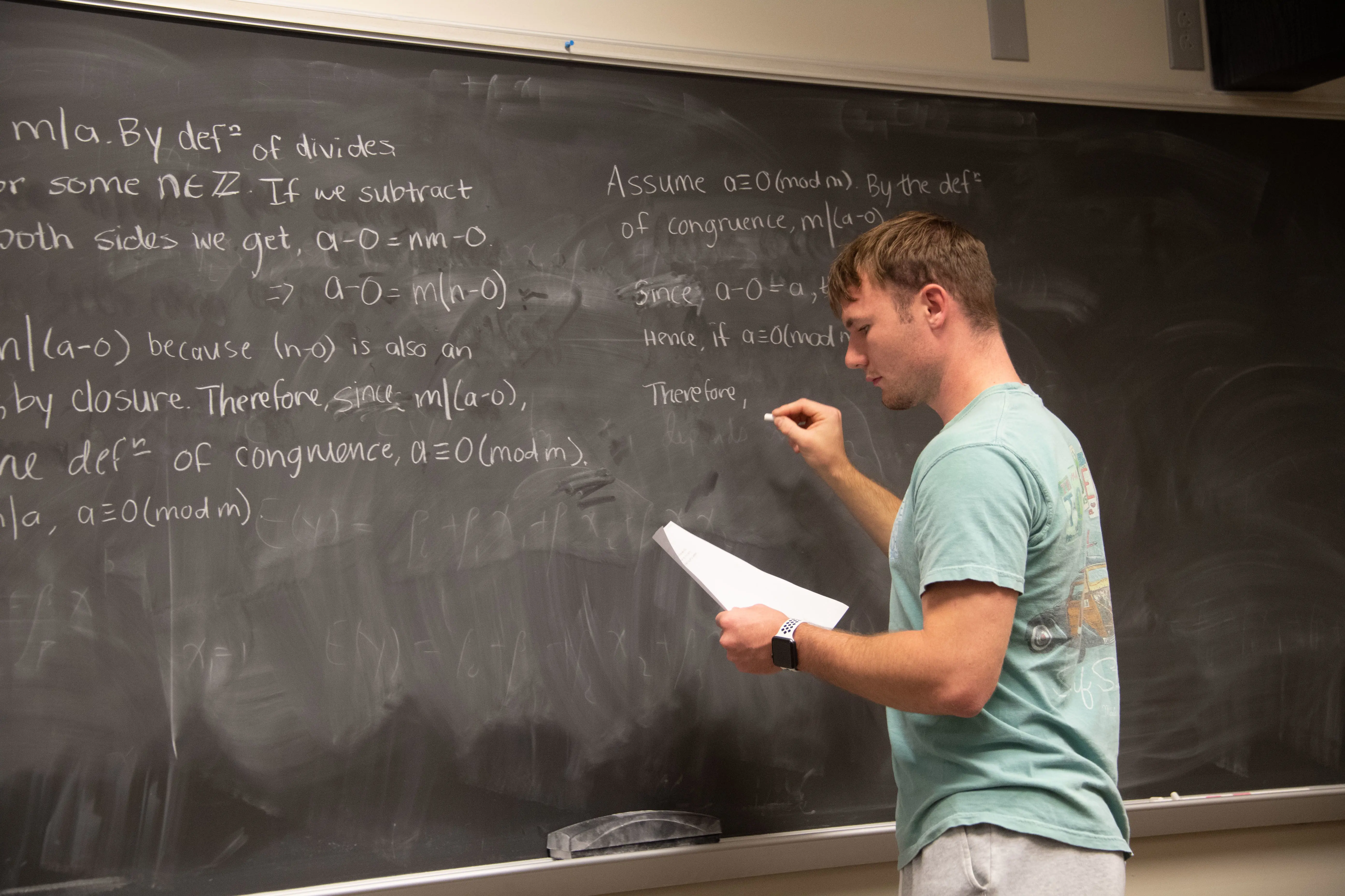 Student writing on the chalkboard in a mathematics class