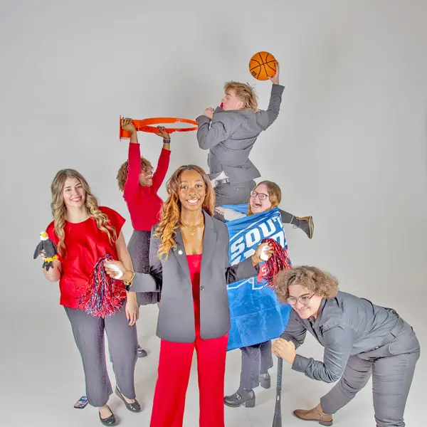 The executive committee of Student Government Association play and cut up with athletic props in the photo studio.