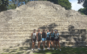 OT students and a faculty member pose for photo in front of a wall