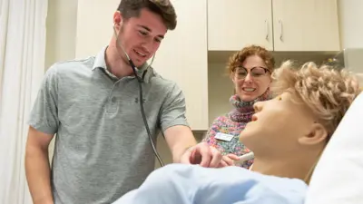 A student in the simulation lab checking the heart rate of a sim mannequin 