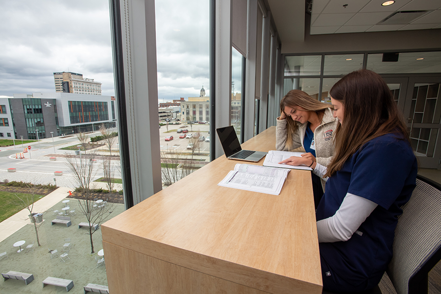 Students studying by a window with view of Downtown Evansville
