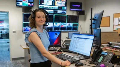 Student wears a headset standing in the USI TV studio
