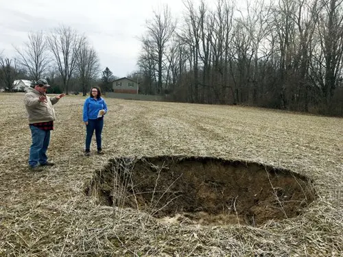 Environmental science student speaks with a landowner about a hole in his field