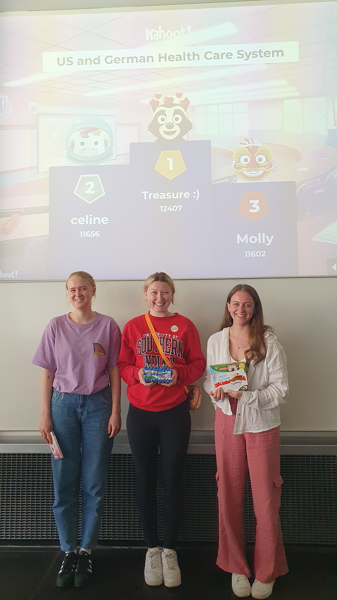 Three students pose for photo in front of a screen