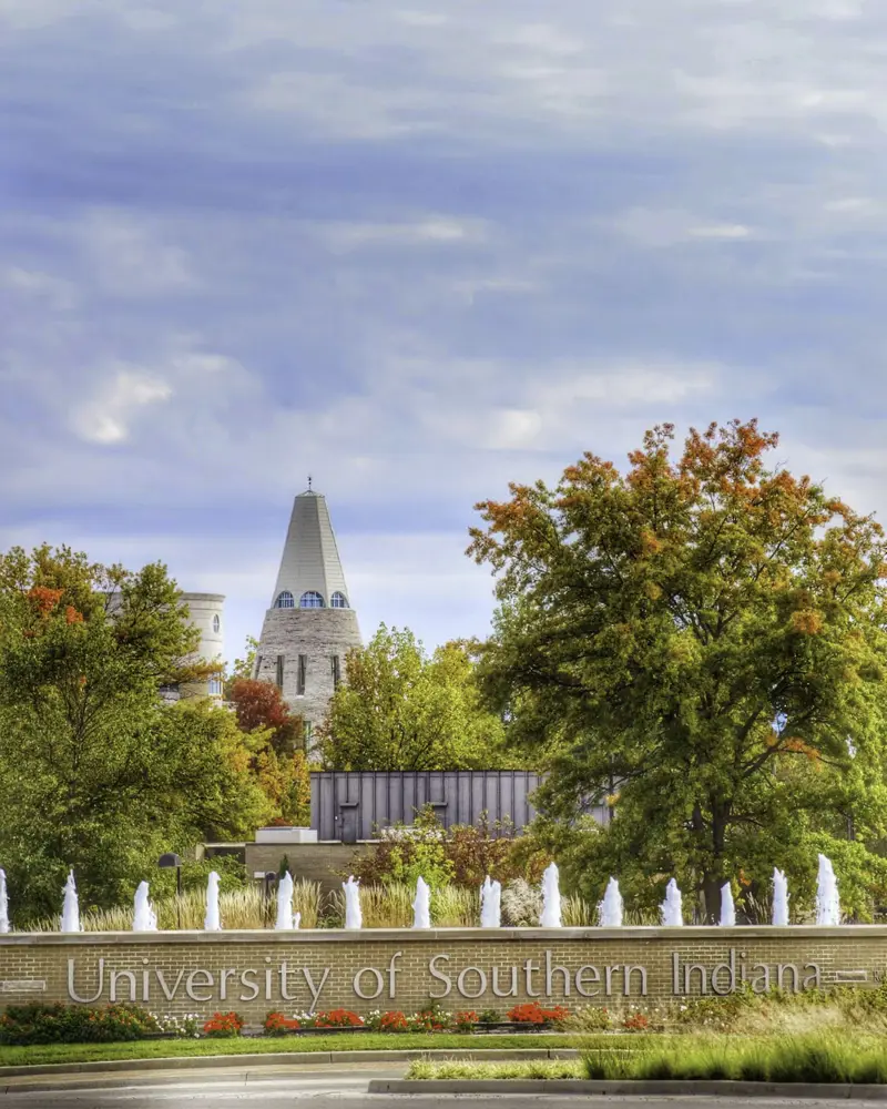 View of the entrance to campus featuring the fountain and the University Tower, with the leaves changing color