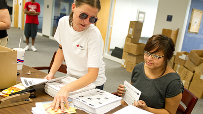 A couple of students sort and stuff mail for the American Red Cross