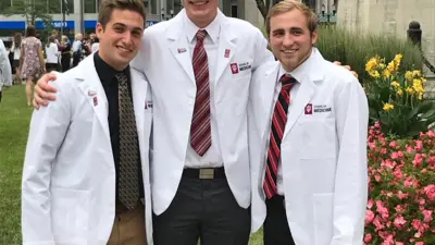 Three pre-medical students pose for a photo in their white lab coats