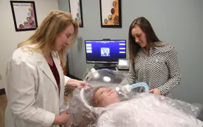 Faculty member and students using equipment 