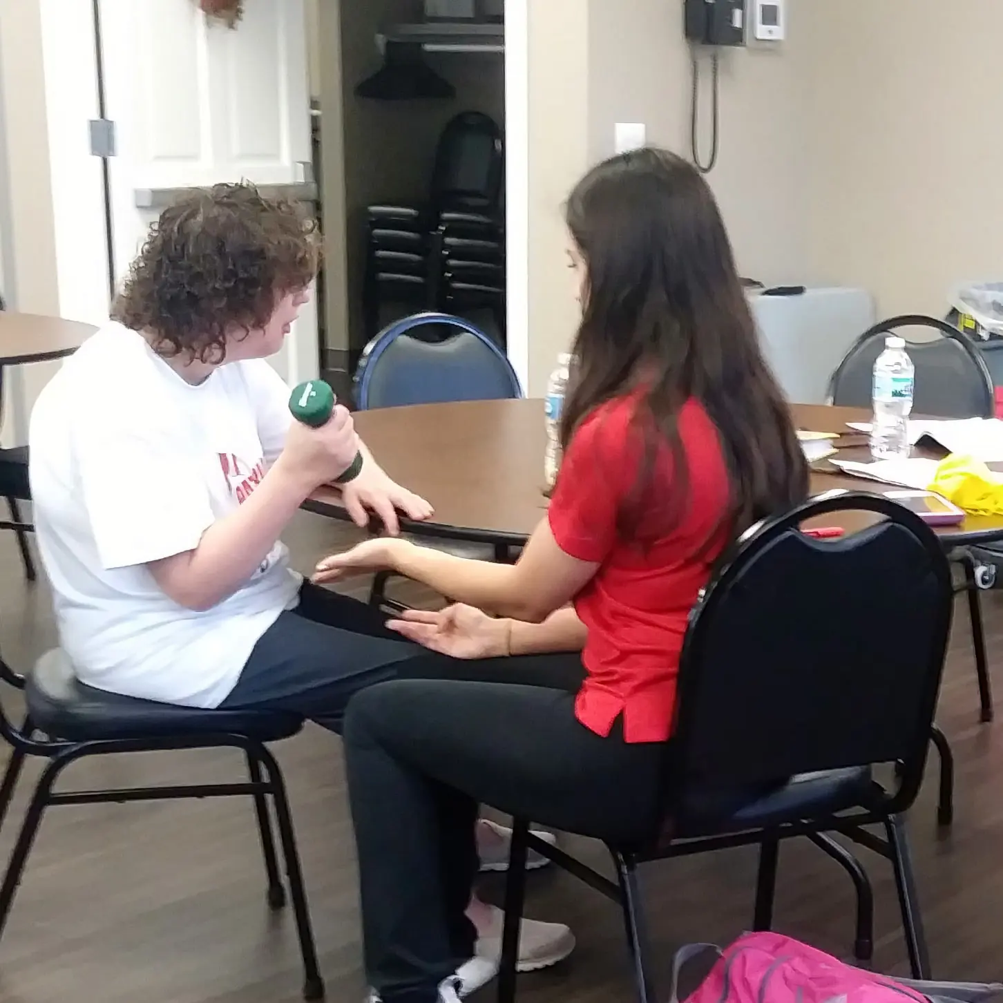 Pre-Occupational Therapy student assists a patient curling with a small dumbbell