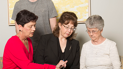 Nurse practitioner looking at medical chart with older adult, her daughter and grandson