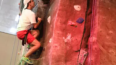 Student climbs the rock wall in the Recreation, Fitness, and Wellness Center