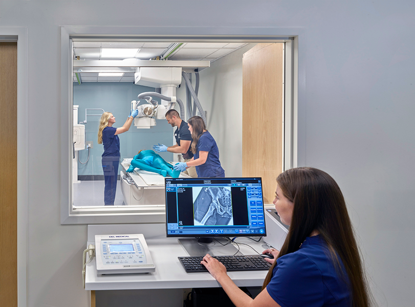 Students working in an X-ray room with monitor on outside showing the X-ray