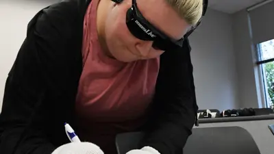 Photo of student wearing gloves and trying to use a pen to write