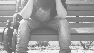 Moody black and white portrait of a man looking away from the camera with his hands on his head