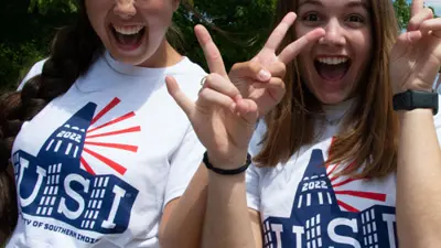 Two students throw peace signs in their USI t-shirts