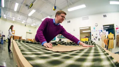 Student cutting fabric to pattern in the Costume Shop