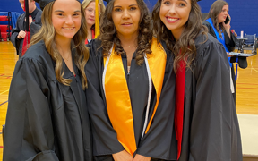 Three health administration students wearing graduation caps and gowns