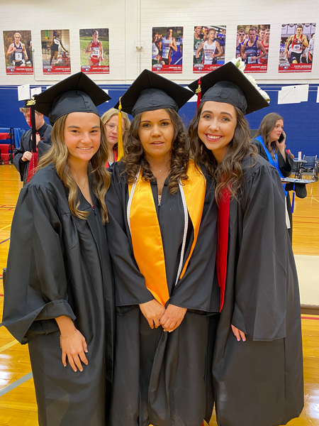 Three health administration students wearing graduation caps and gowns