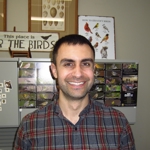 Casual portrait of Dr. Alex Champagne with educational materials about birds in the background
