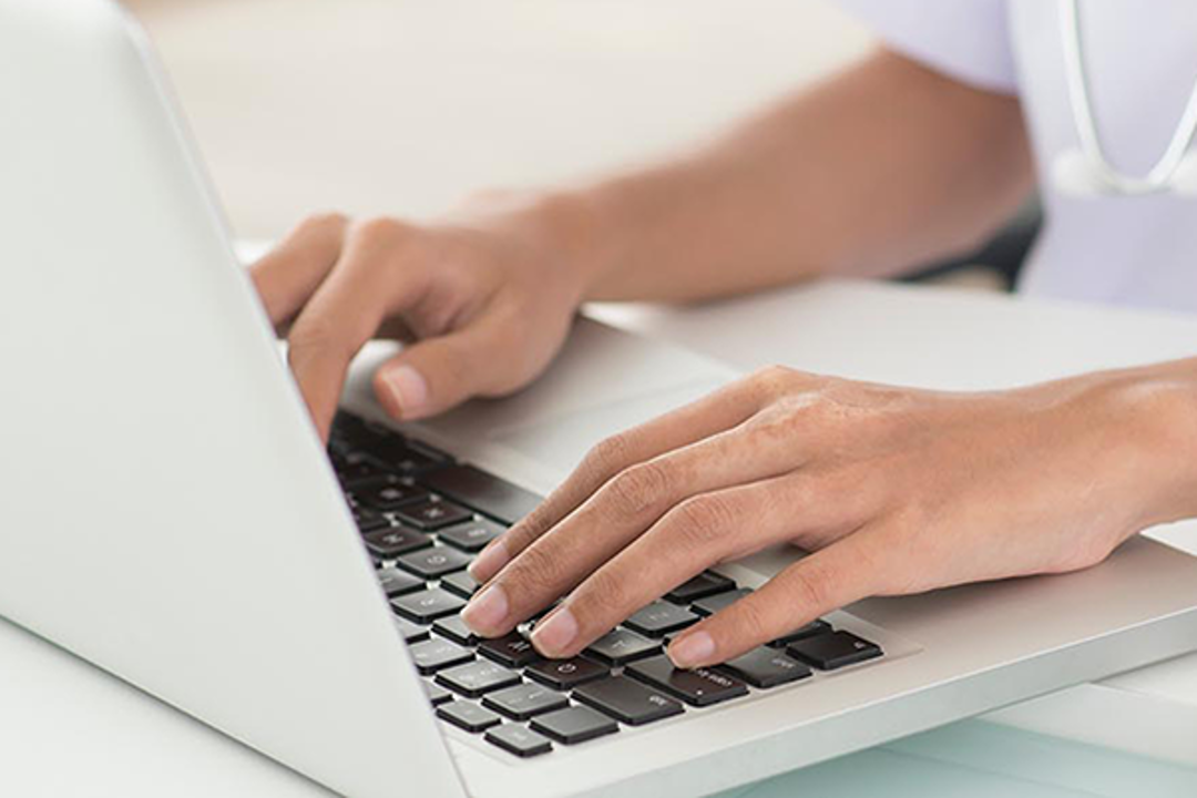 photo of hands typing on a laptop keyboard