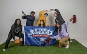 Members of Activities Programming Board pose on the astroturf in the studio and play with the athletic props for their group photo.