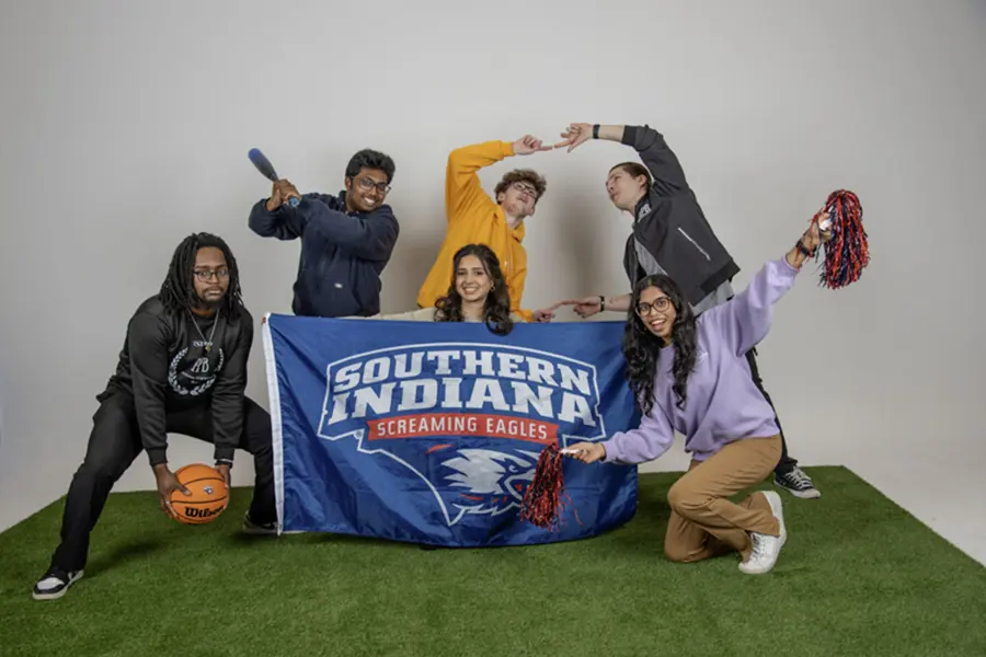 Members of Activities Programming Board pose on the astroturf in the studio and play with the athletic props for their group photo.