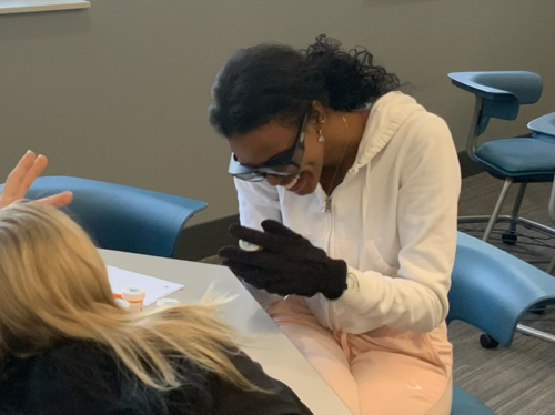 students wearing gloves and attempting difficult tasks in mobility simulation
