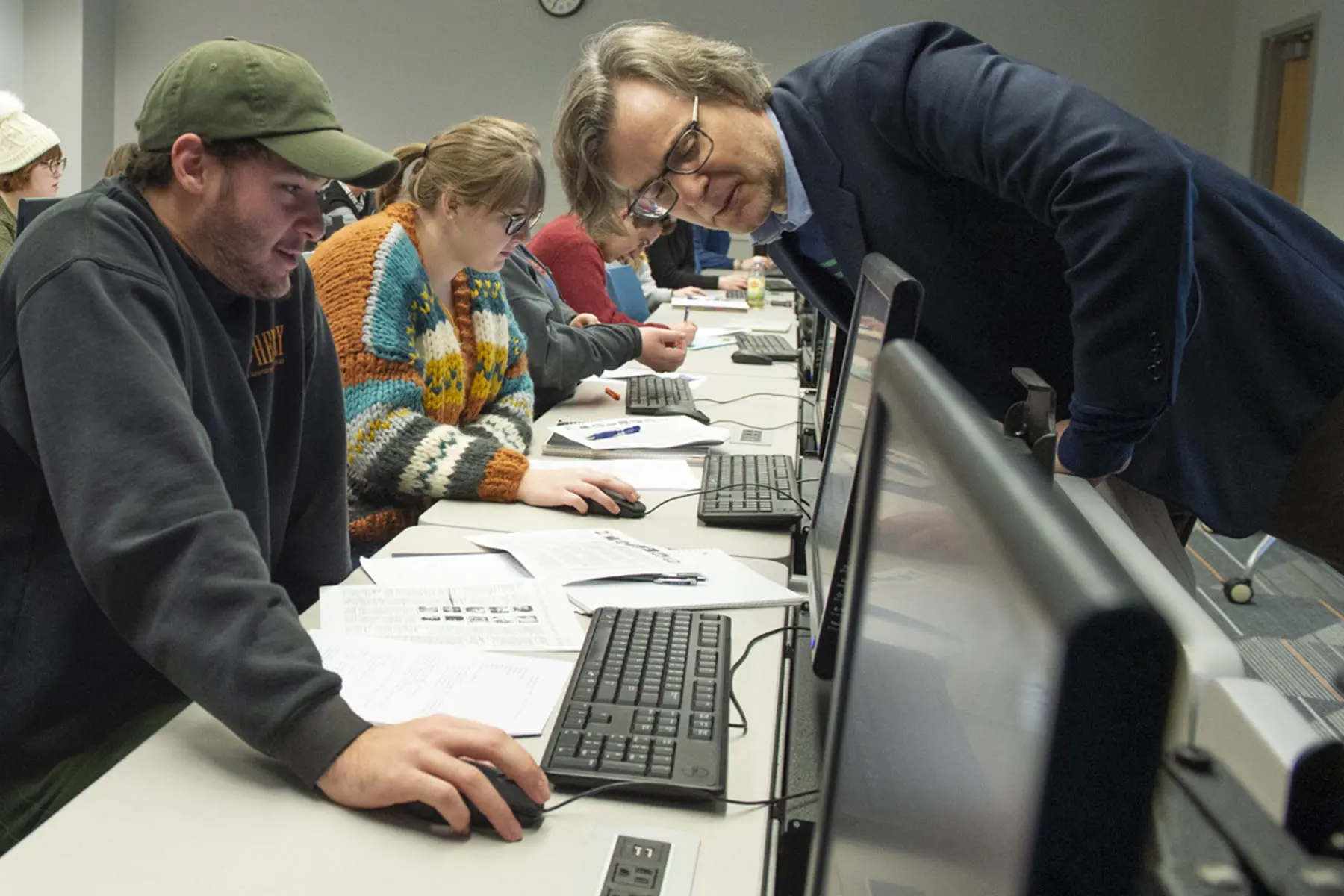 A sociology professor assists a student with his assignment in a computer lab