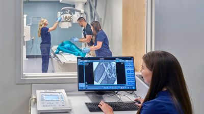 Student at computer monitor looking at image being scanned in X-ray room