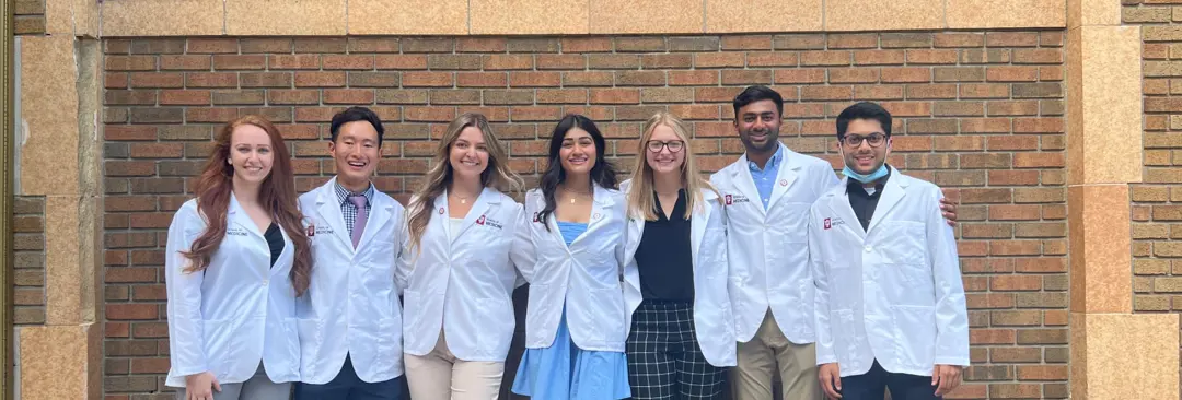 Group of pre-medical sciences students pose in white labs