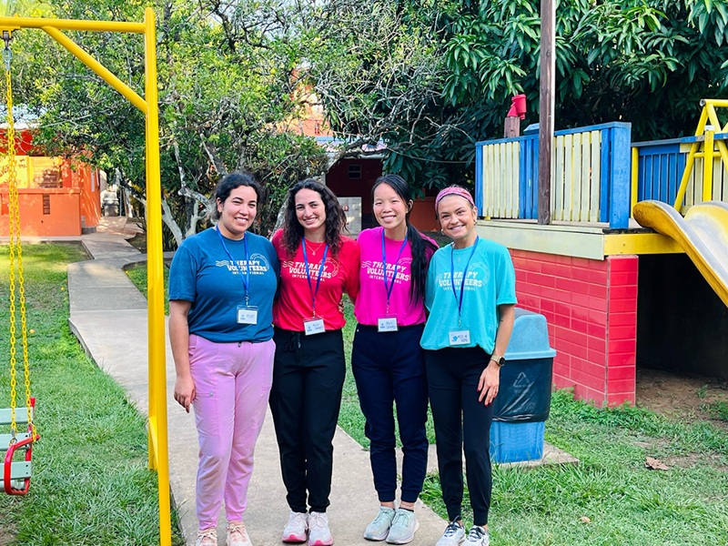 Four OT students pose for photo on playground