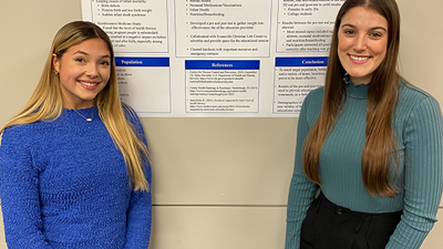 Photo of two students in front of their poster