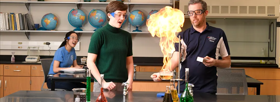 Chemistry faculty and student wear safety glasses while they work on a flaming science experiment