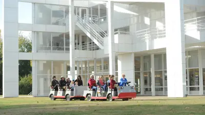 Tourists ride an outdoor tram in front of Historic New Harmony's Atheneum