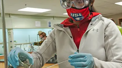 Chemistry student performs a lab experiment in protective personal equipment