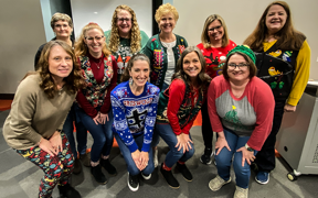 Group photo of Kinney College faculty and staff in holiday sweaters